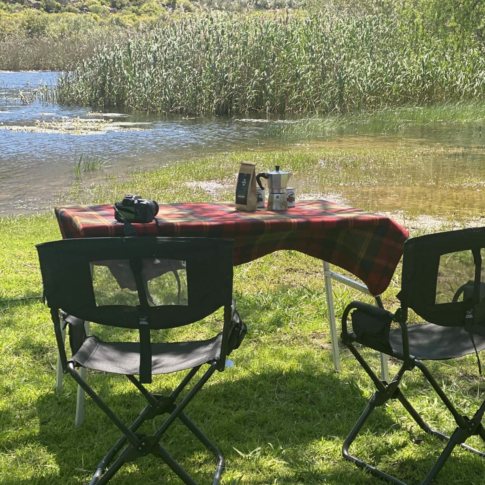 Alu-Cab Campingtisch aus Aluminium mit Gasdruckfedern. Gedeckter Tisch und zwei Campingstühle.