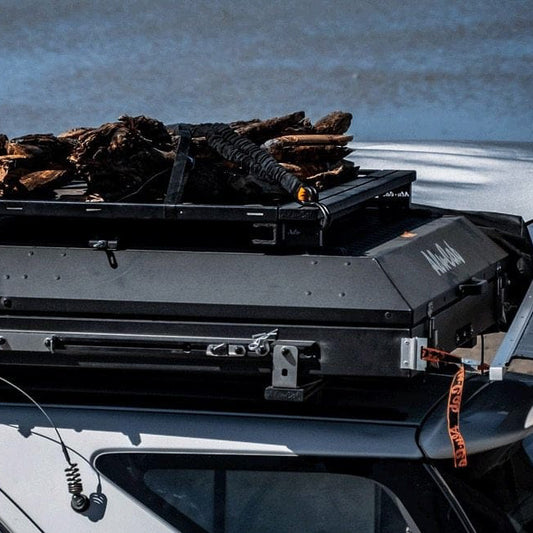 Alu-Cab Dachkorb Tischhalterung. Diese wird zwischen Dach und Dachkorb befestigt und nutzt den Raum zwischen dem Korb und dem Fahrzeug optimal aus. Montiert auf einem Alu-Cab Dachzelt auf einem Offroad Fahrzeug.