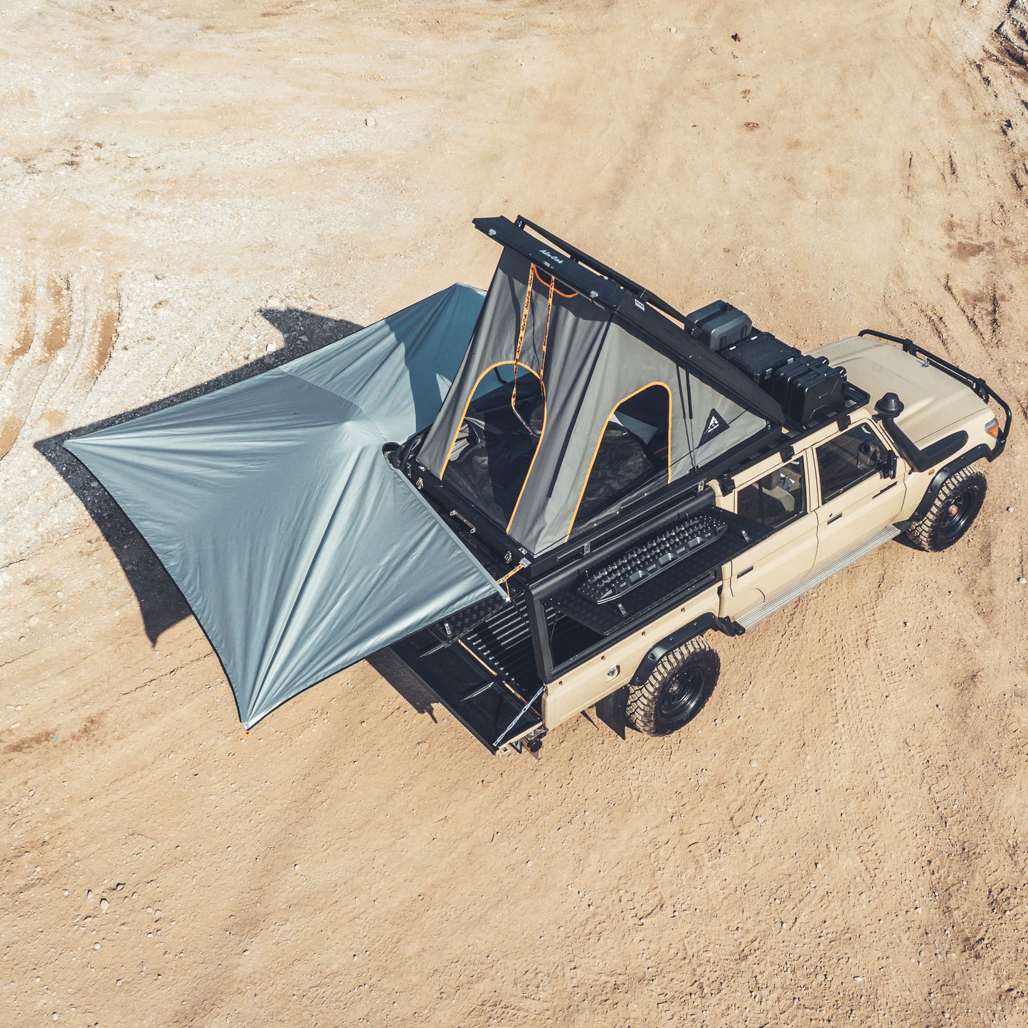 Drohnenaufnahme von der 270° Markise mit grauem Stoff. Die Markise wurde aufgespannt. Montiert an einem Offroad Fahrzeug mit aufgebautem Dachzelt.