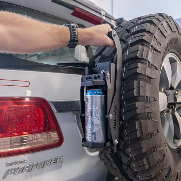 Alu-Cab "Can Crusher" Dosen-Eindrücker wurde am Reserverad eines Offroad Fahrzeuges befestigt. Ein Mann drückt gerade eine Dose zusammen.