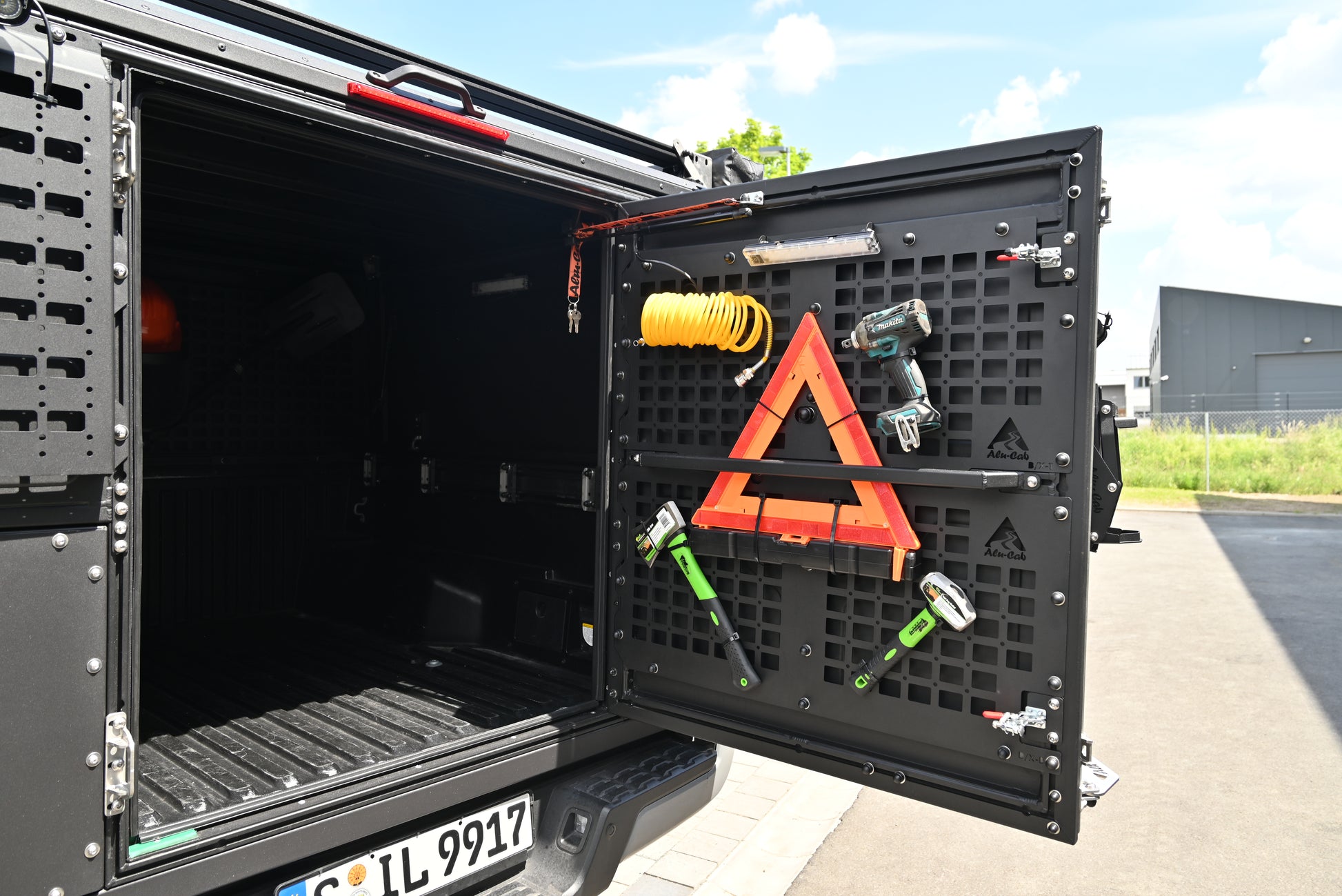 ModCAP Worker Innenraum zu sehen. Montiert auf einem Offroad Fahrzeug. Mit geöffneter Hecktür. Mit montiertem Werkzeug wie Axt und Hammer an den Molleplatten.