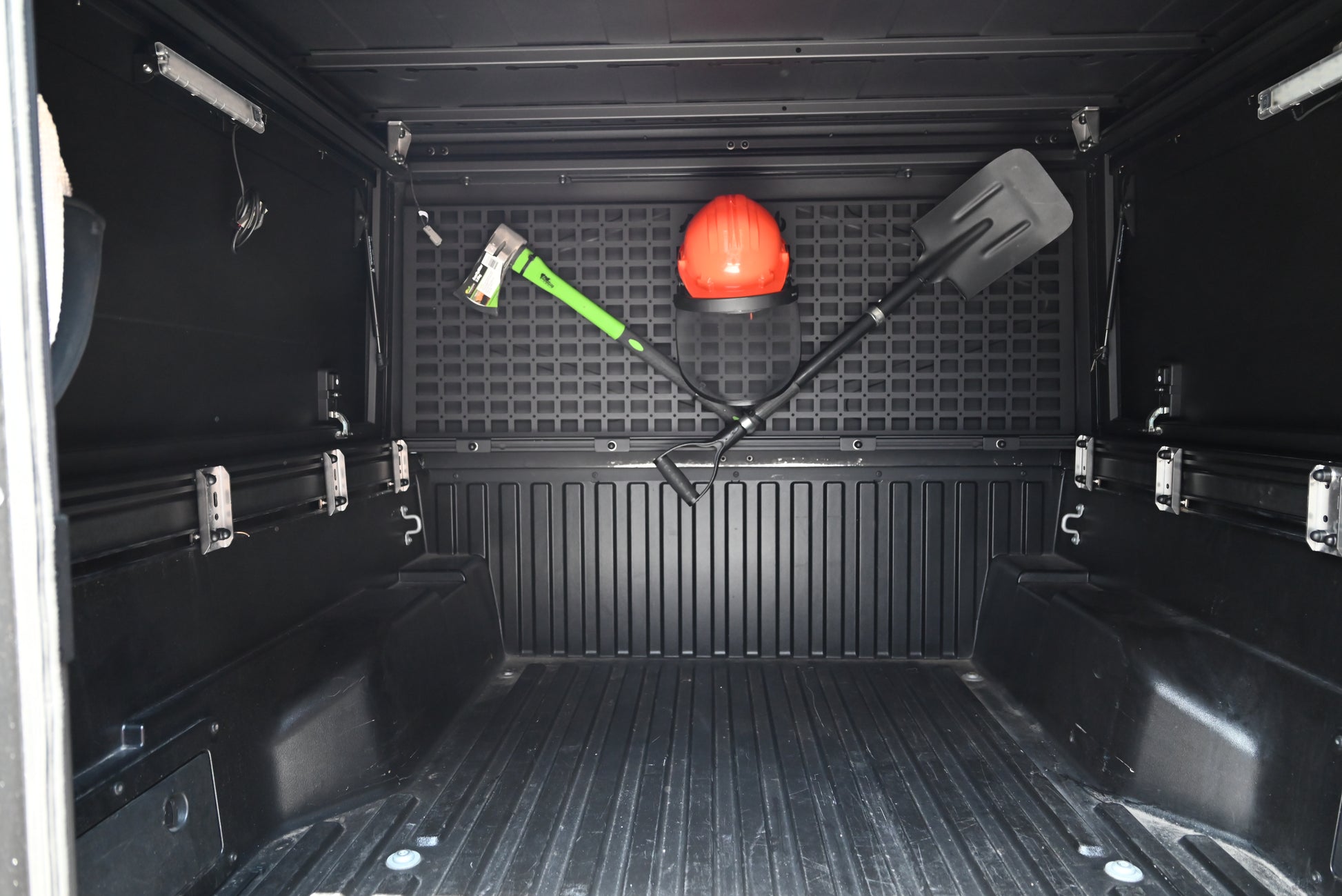 Innenraum des ModCAP Worker. Leer mit geschlossenen Seitenfenster. An der vorderen Wand sind eine Axt, Schaufel und ein Helm an den Molleplatten befestigt.