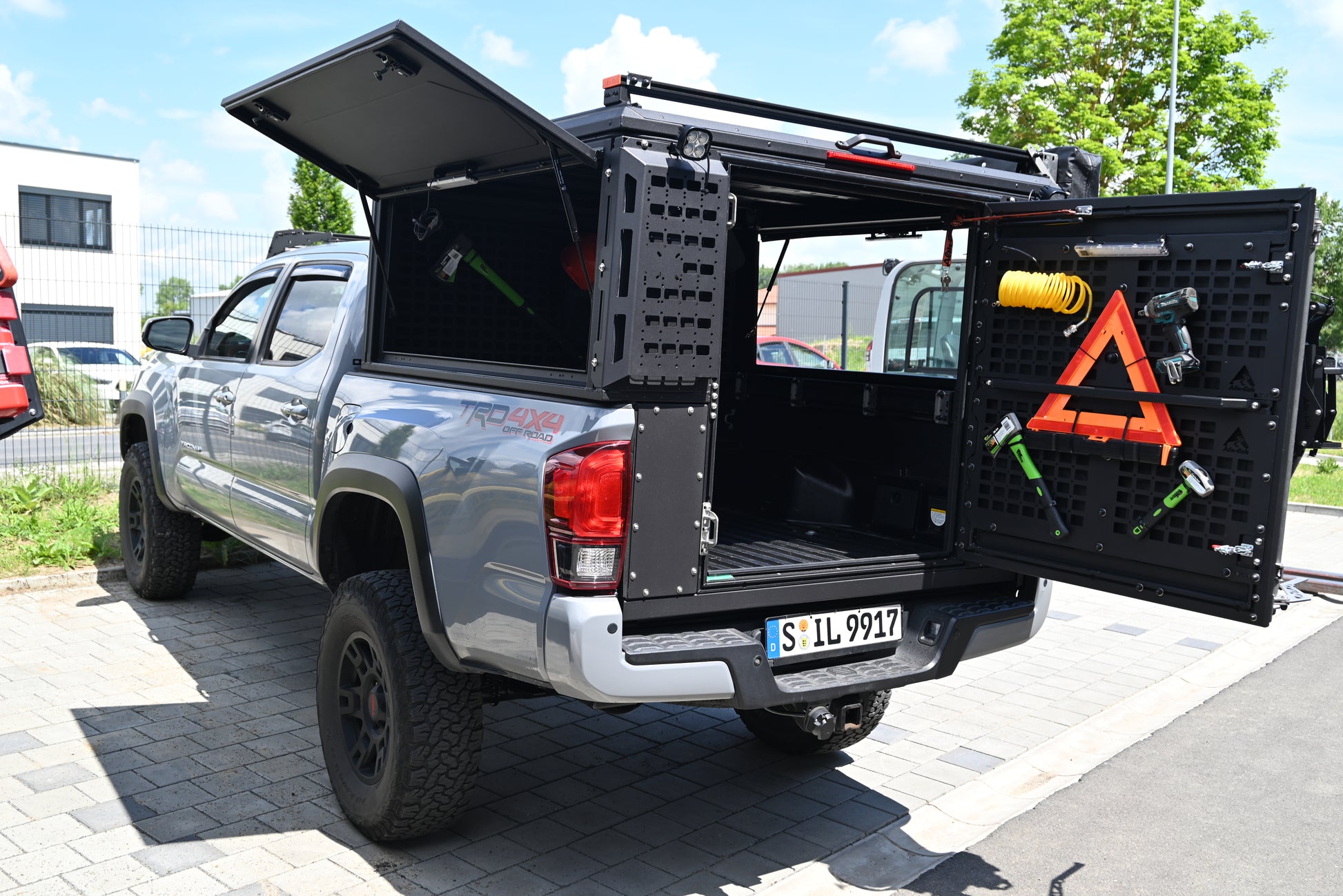 ModCAP Worker Innenraum zu sehen. Montiert auf einem Offroad Fahrzeug. Mit geöffneter Hecktür und Seitentüren. Mit montiertem Werkzeug wie Axt und Hammer an den Molleplatten.