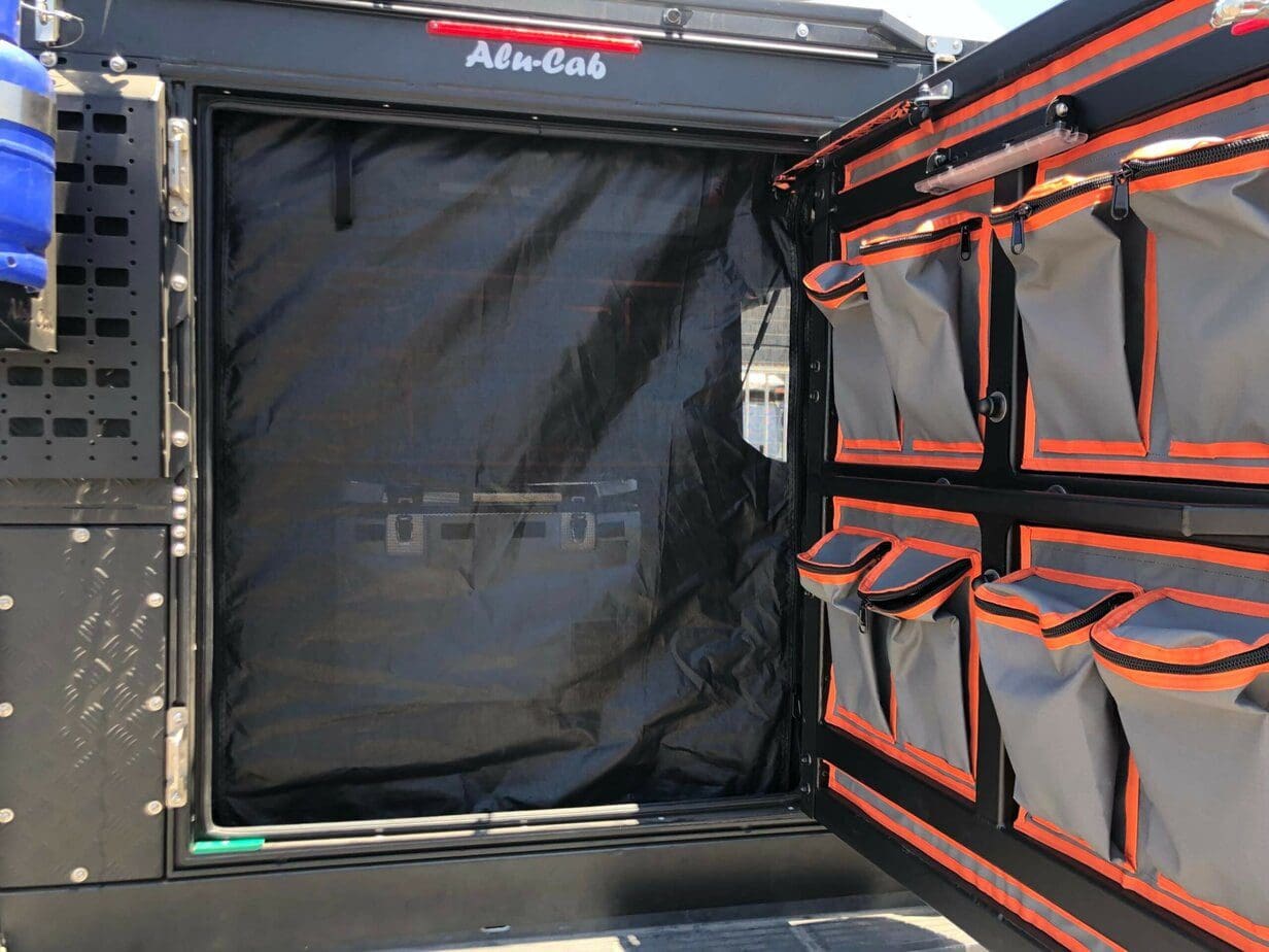 Moskitonetz wurde in dem Seitenfenster des Alu-Cab ModCAP´s gespannt. Es schützt vor Insekten, während es frische Luft in den Camper lässt. Zusätzlich wurden Taschen an der Hecktür befestigt.